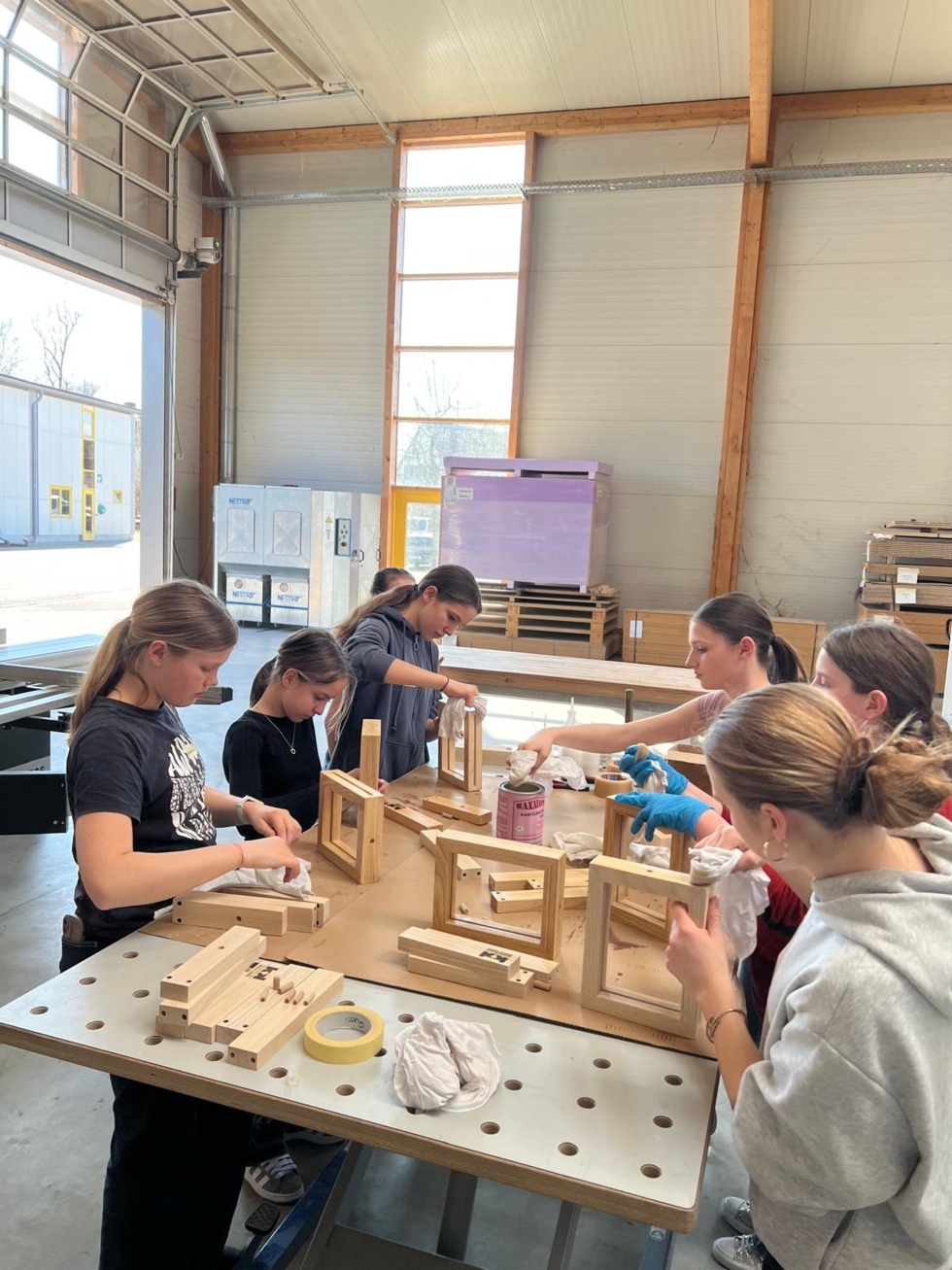 Teilnehmerinnen des Girls' Day arbeiten konzentriert an Holzprojekten in einer Werkstatt