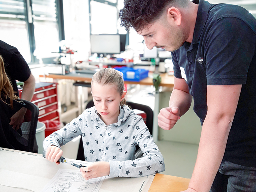 Eine Teilnehmerin des Girls' Day arbeitet an einer XY-Justieraufnahmeplatte OH 40, während ein Mitarbeiter ihr Anweisungen gibt