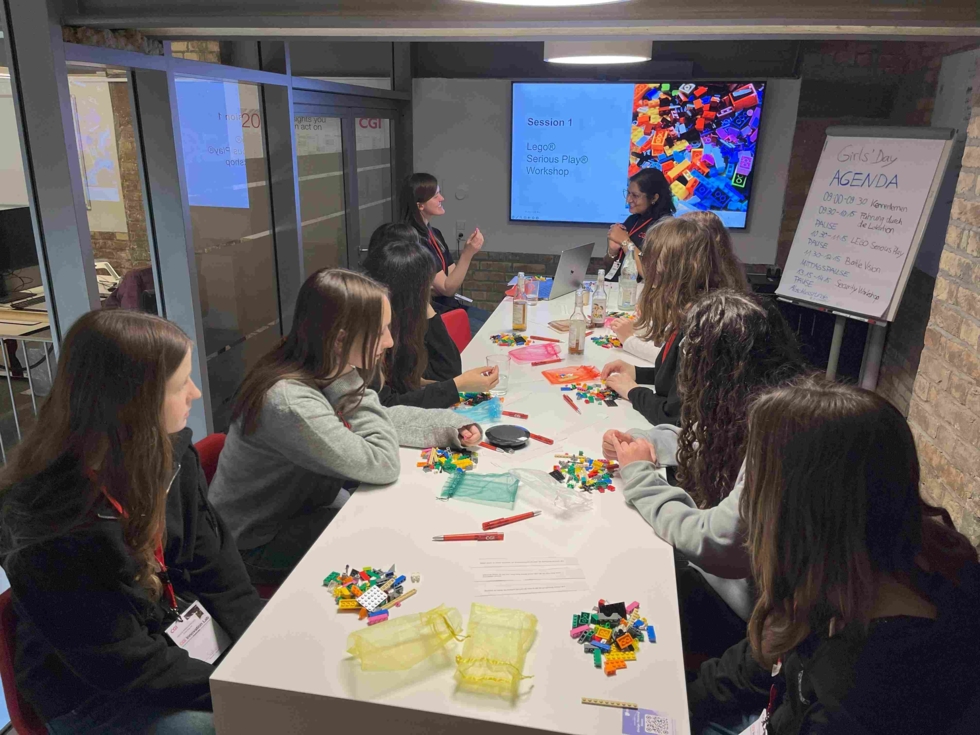 Girls' Day-Teilnehmerinnen bei einem LEGO-Workshop, sitzen an einem Tisch und arbeiten an Projekten.