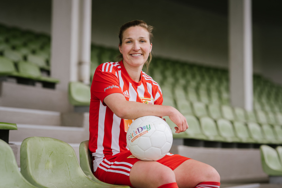 Fußballspielerin auf einer Tribüne mit Fußball