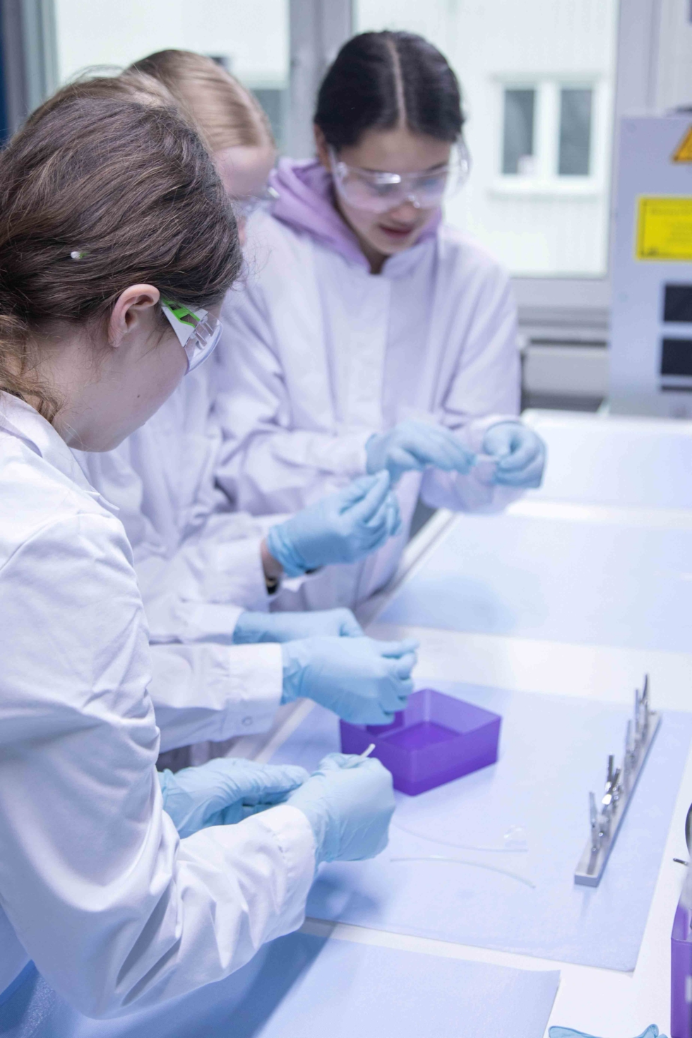 Girls'Day-Teilnehmerinnen mit Schutzanzügen im Labor