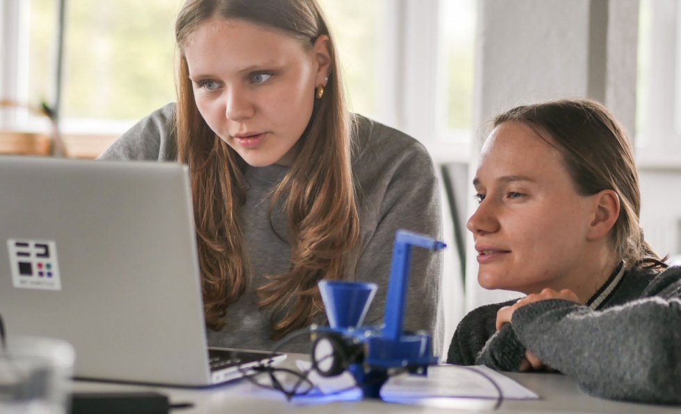 Zwei Frauen vor einem aufgeklappten Laptop.