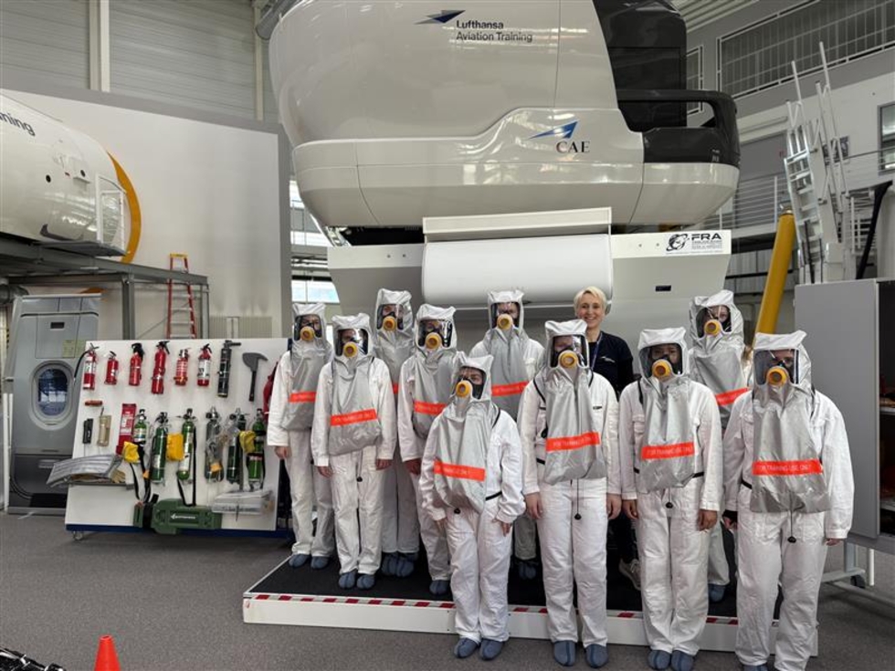 Gruppenbild mit Schutzanzügen und Atemmasken in einem Hangar