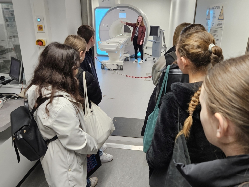 Eine Gruppe von Menschen steht vor einem MRT-Gerät.