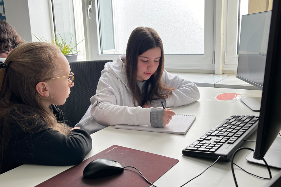 Zwei Mädchen sitzen vor einem Computer