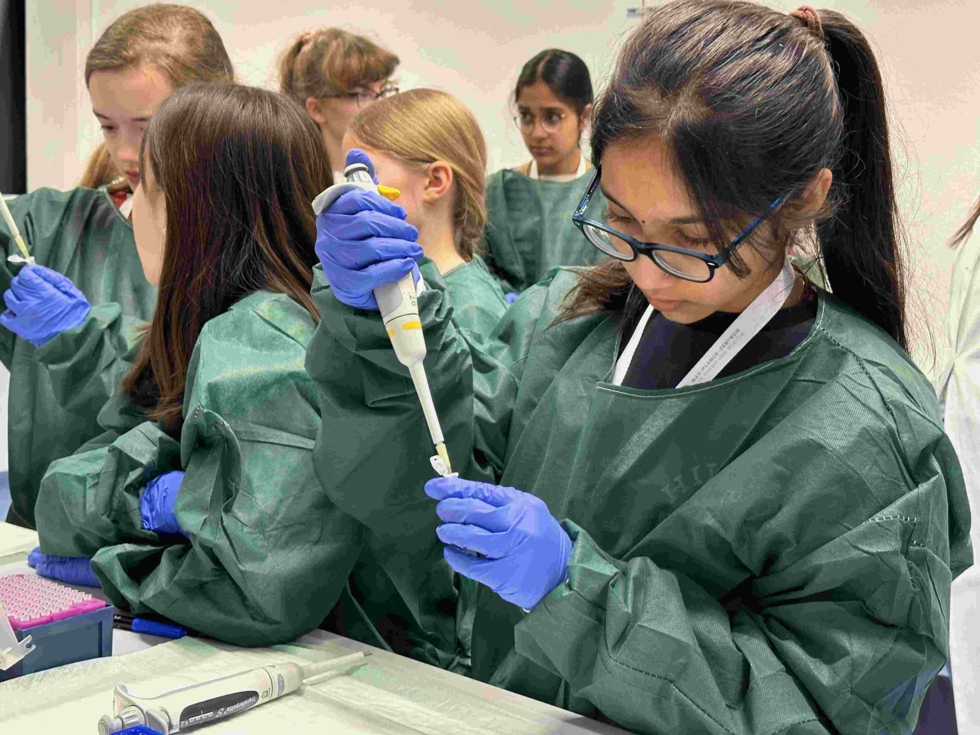 Girls'Day-Teilnehmerinnen mit Schutzanzügen experimentieren