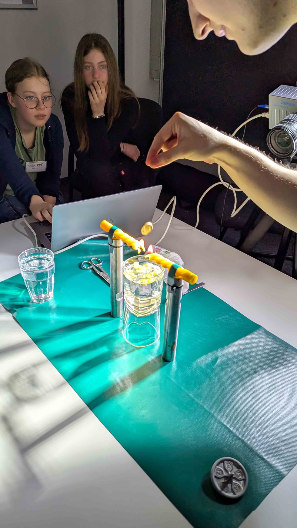 Mitarbeiter zeigt Girls'Day-Teilnehmerinnen Experiment mit Kerzen