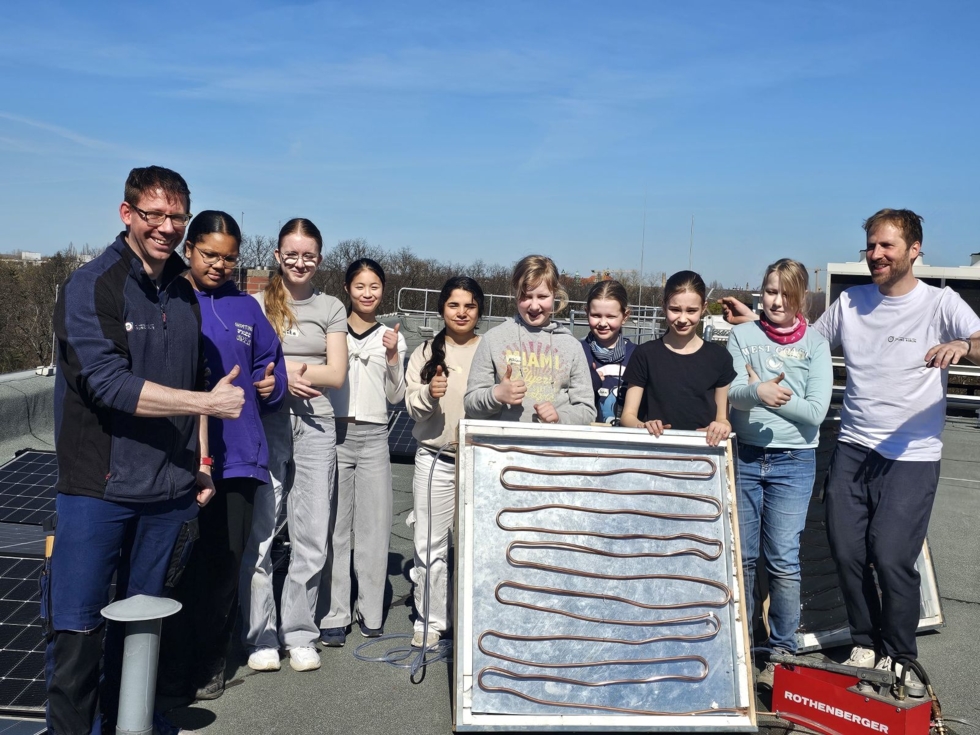 Ein Foto von den Girls' Day Teilnehmerinnen mit den Mitarbeitenden wie sie den selbst gebauten Solarkollektor präsentieren
