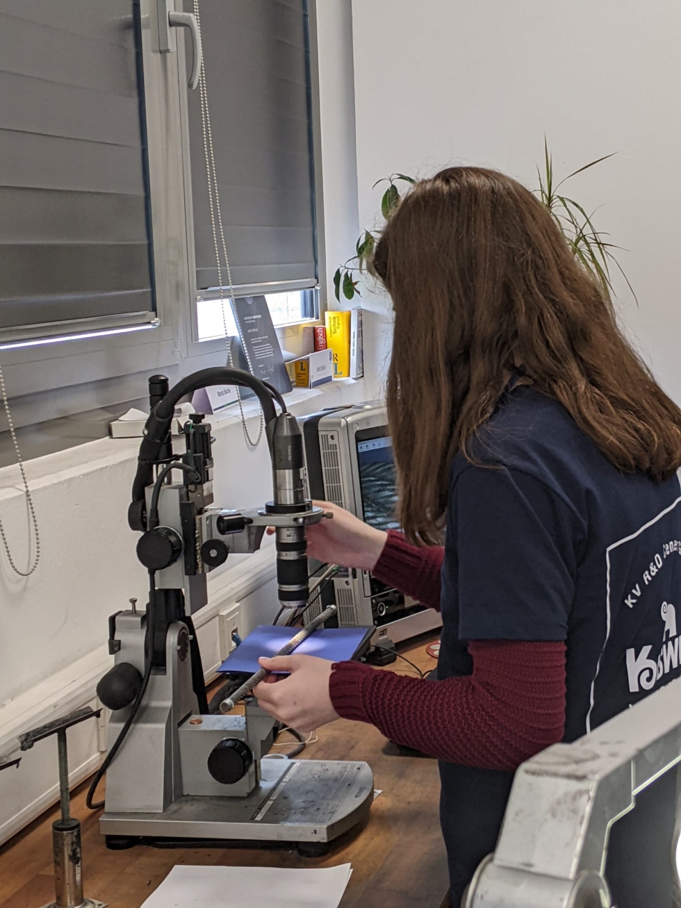 Girls'Day-Teilnehmerinnen mit Mikroskop an der Werkbank