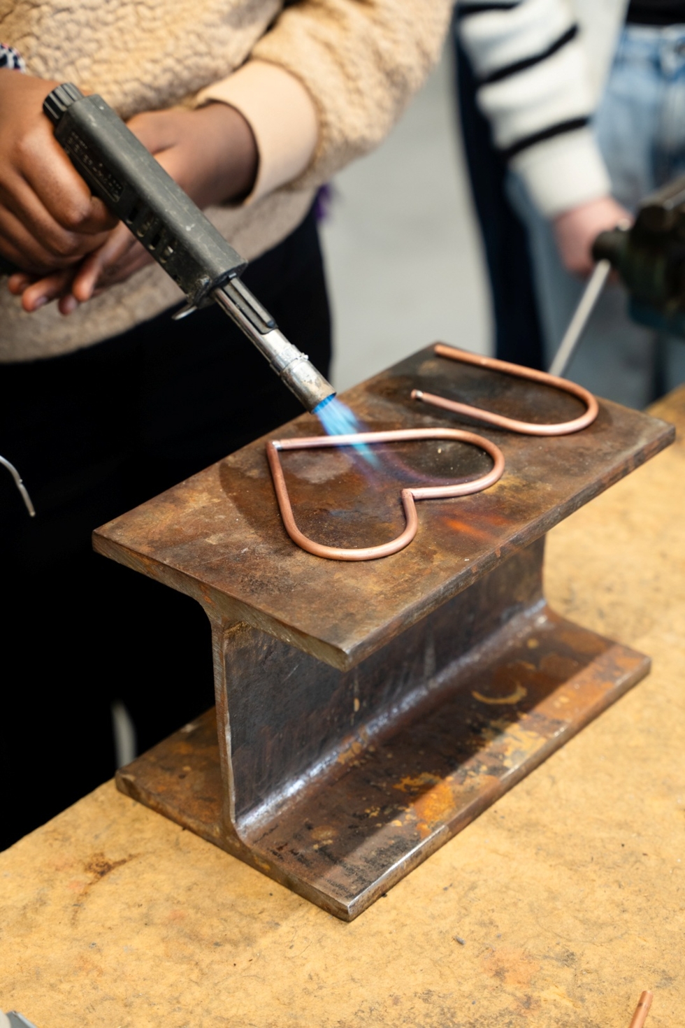 Girls' Day-Teilnehmerin erhitzt mit Brenner ein kupfernes Herz auf einem Metallblock