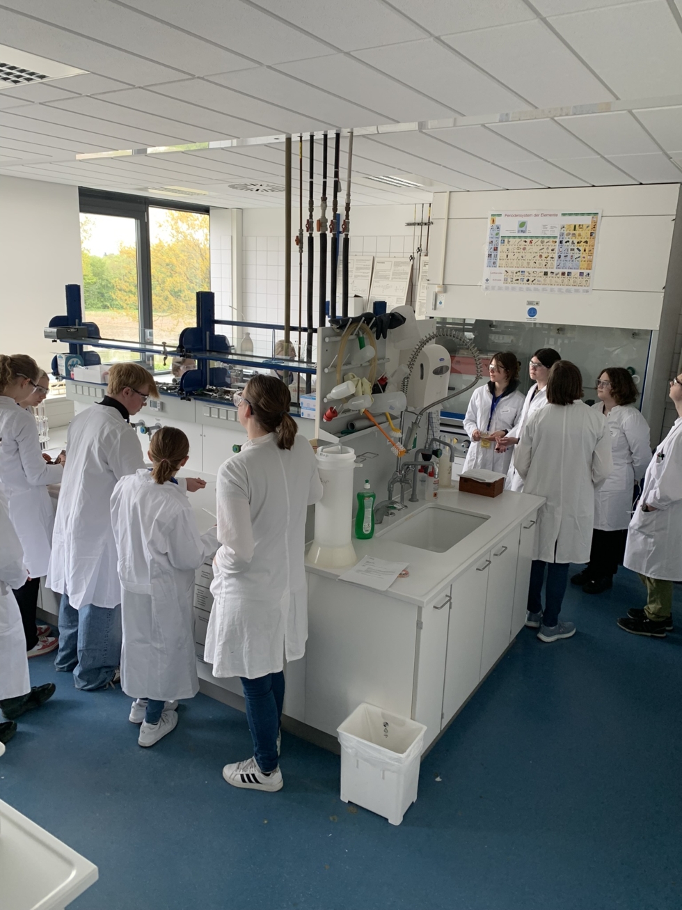 Girls'Day-Teilnehmerinnen mit Kitteln im Labor