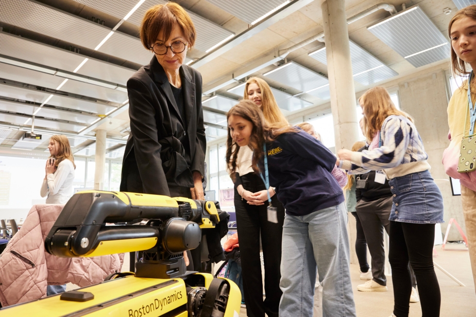 Mehrere Schülerinnen mit Roboter-Hund und Ministerin