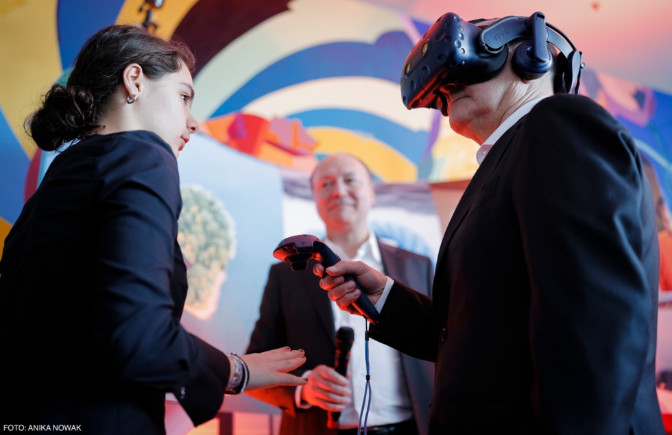 Teilnehmerin mit Bundeskanzler Olaf Scholz, der eine 3D-Brille trägt.