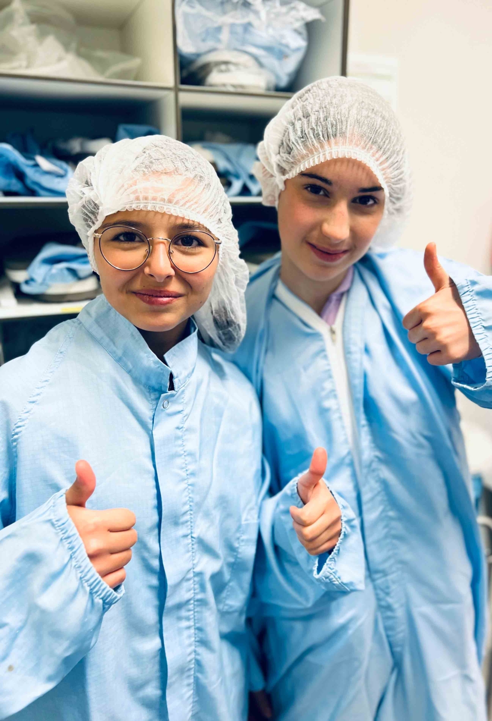 Girls'Day-Teilnehmerinnen mit Schutzanzügen und Dauemn hoch