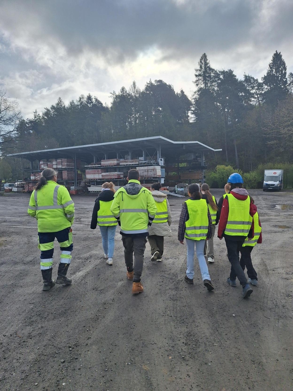 Gruppenbild von hinten mit Girls'Day-Teilnehmerinnen in Warnwesten gehen über den Betriebshof