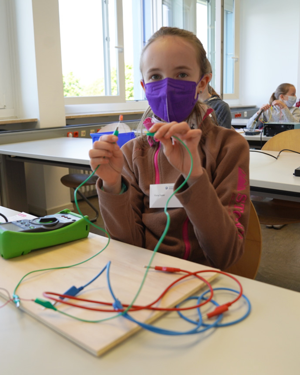 Mädchen mit Maske verbindet zwei Kabel
