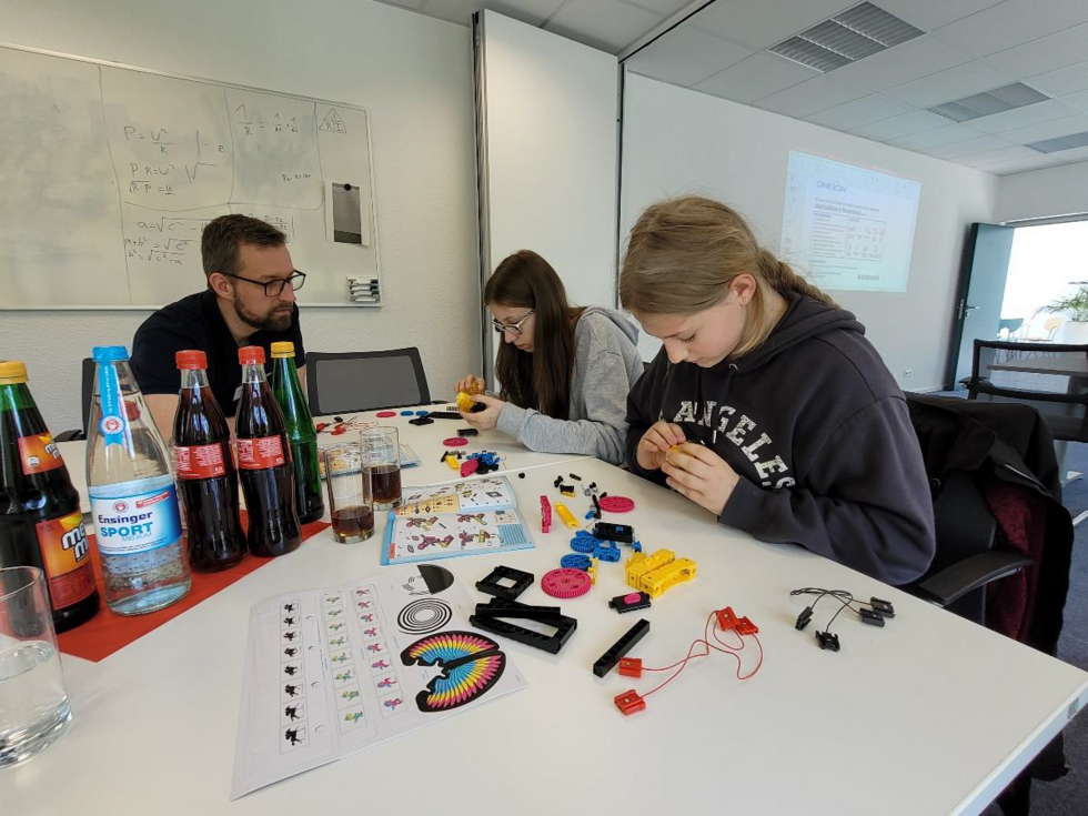 Zwei Mädchen am Tisch hantieren mit Bauteilen und Kabeln