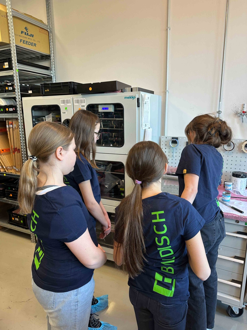 Girls'Day-Teilnehmerinnen schauen sich Geräte in Werkstatt an