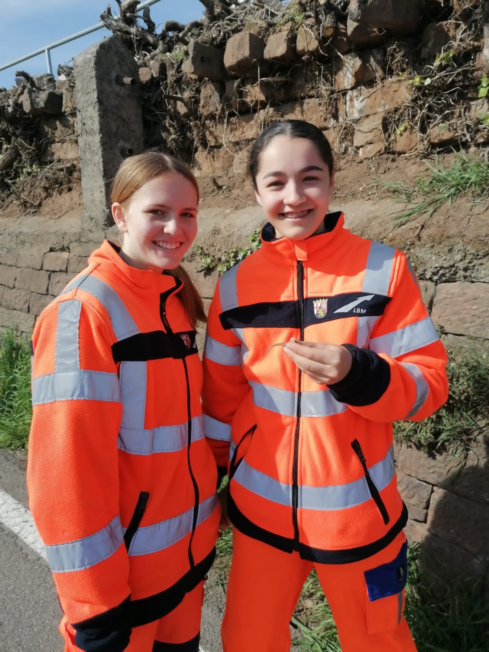 Girls'Day-Teilnehmerinnen in Straßenwärterinnenkleidung mit Eidechse in der Hand