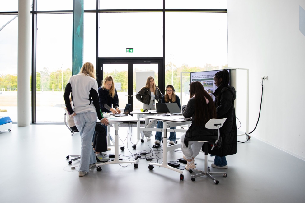 Eine Gruppe von Personen sitzt in einem Büro und arbeitet an Laptops.