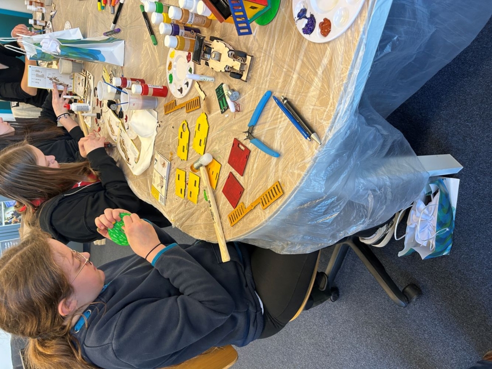 Girls' Day Teilnehmerinnen am Tisch beim Basteln und Malen mit verschiedenen Bastelmaterialien und Farben.