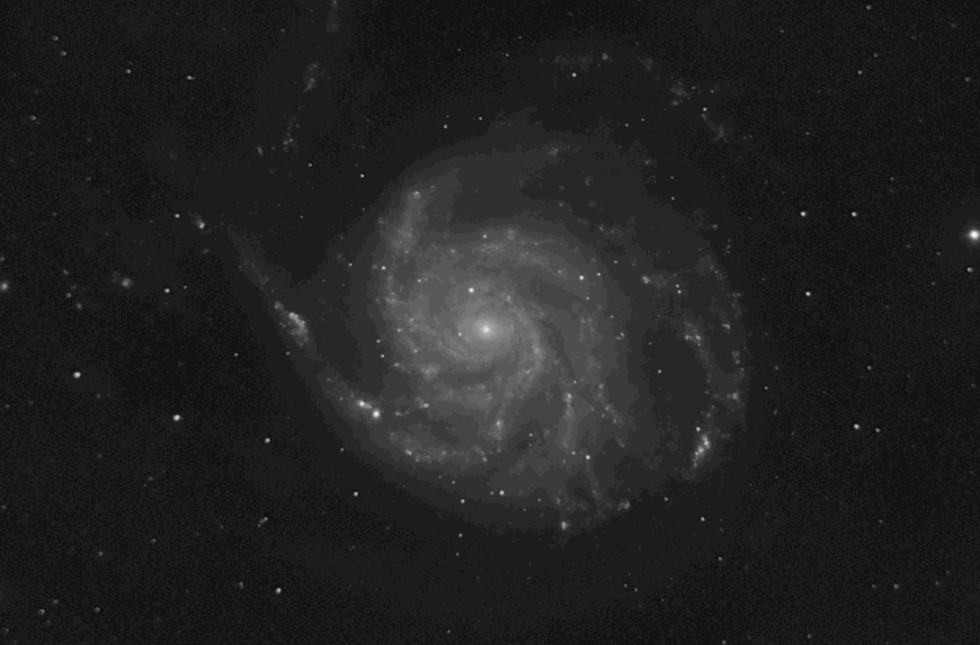 Schwarz-weiß Bild einer Spiralgalaxie mit leuchtenden Sternen und einem zentralen hellen Kern