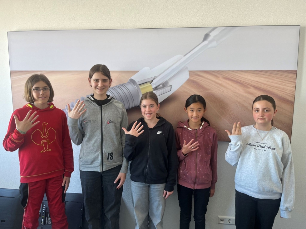 Fünf Girls' Day-Teilnehmerinnen zeigen stolz ihre Titanringe, die sie selbst gefertigt haben