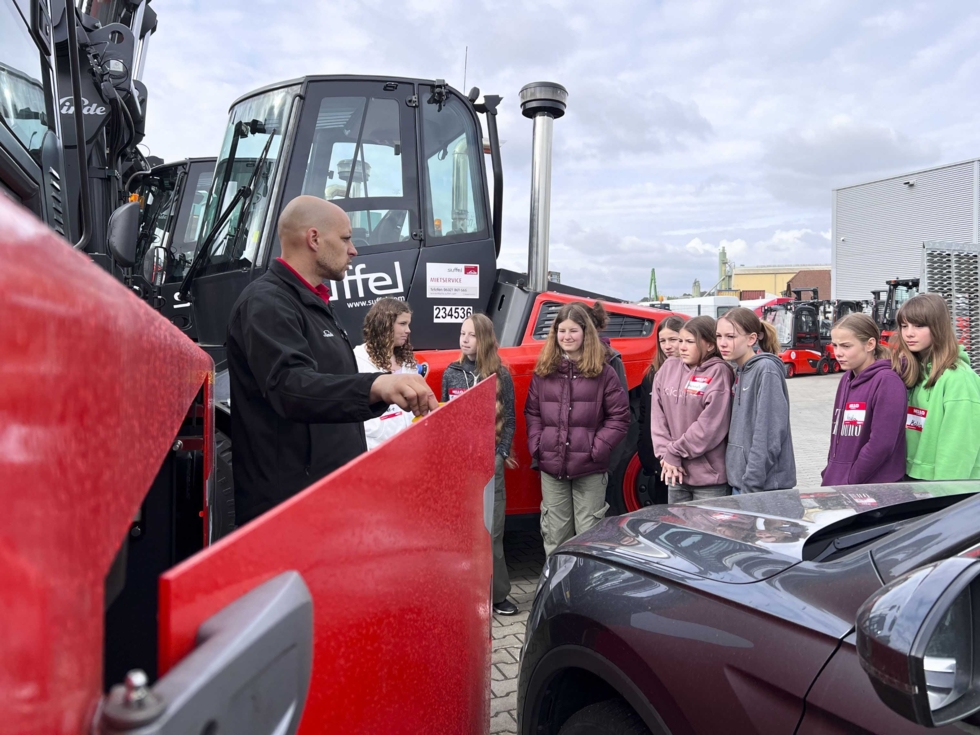 Girls'Day Teilnehmerinnen mit Blick in den Motorraum eines Gabelstaplers