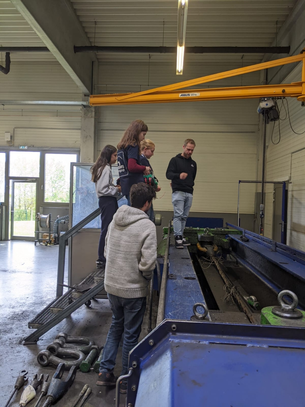 Girls'Day-Teilnehmerinnen mit Mitarbeiter an einer Maschine