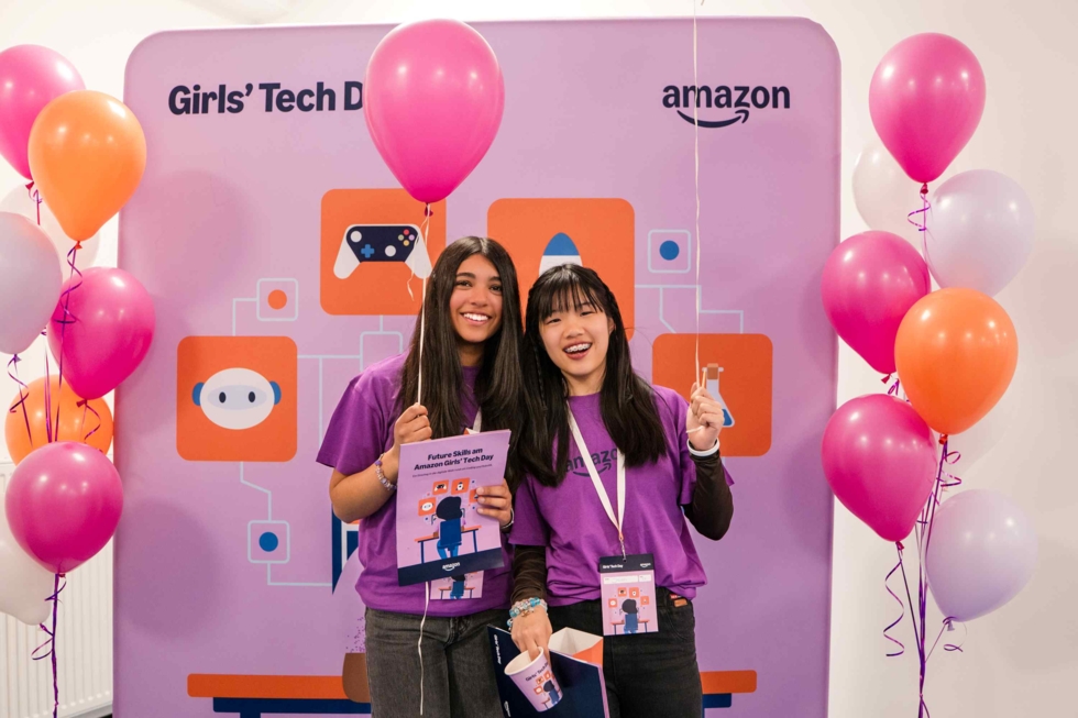 Zwei Mädchen mit Luftballons vor einer Amazon-Wand