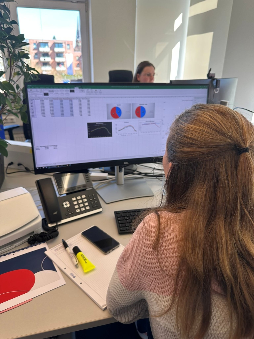 Teilnehmerin des Girl's Day arbeitet am Computer, analysiert Daten auf einem großen Bildschirm.