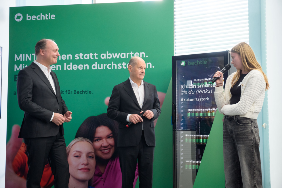 Bundeskanzler Olaf Scholz, Marc Reinhardt von der Initiative D21 und eine Teilnehmerin stehen neben einem Kühlschrank mit Medikamenten.