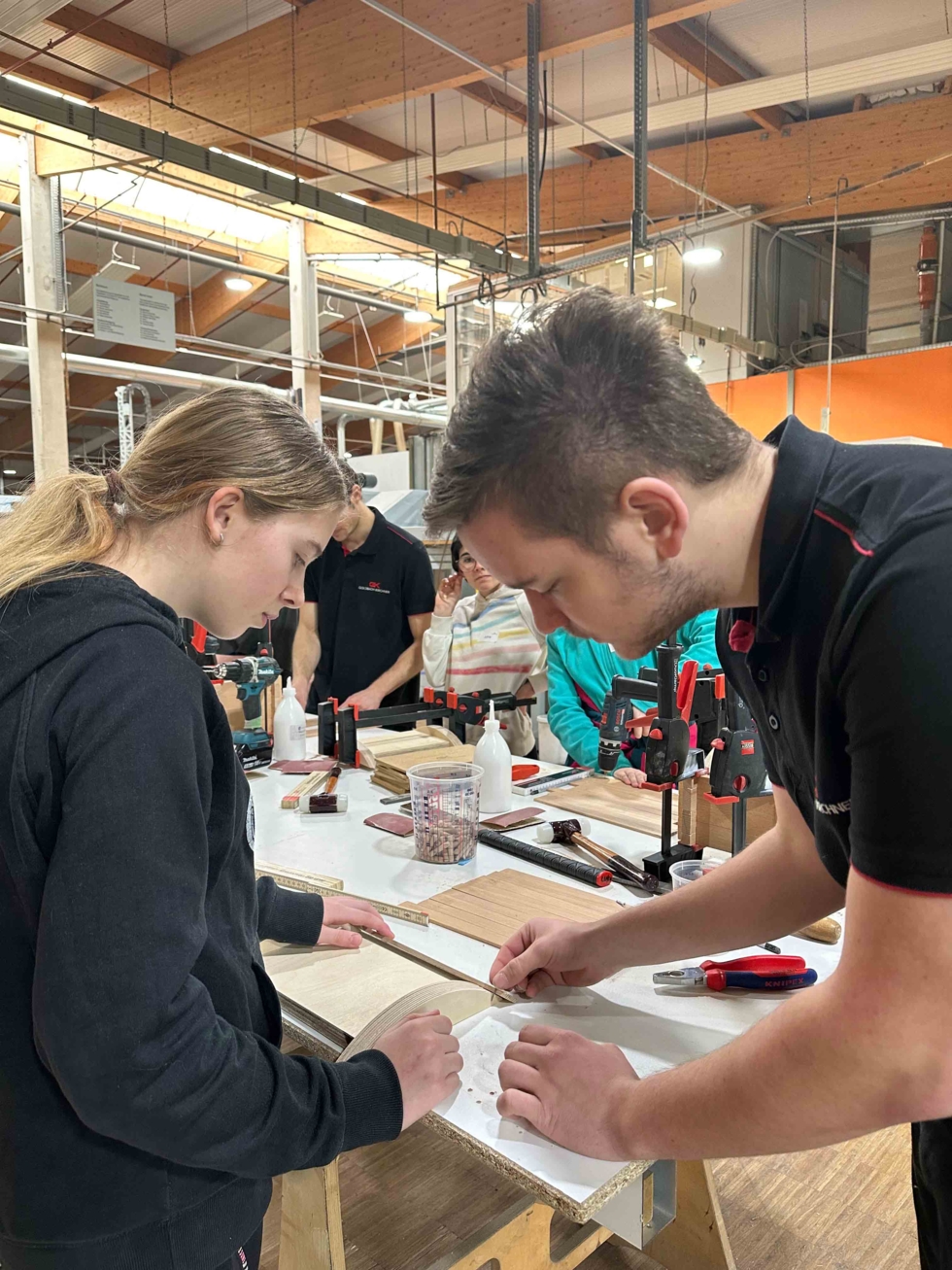 Girls'Day-Teilnehmerinnen an der Wrkbank mit Mitarbeiter beim Vermessen