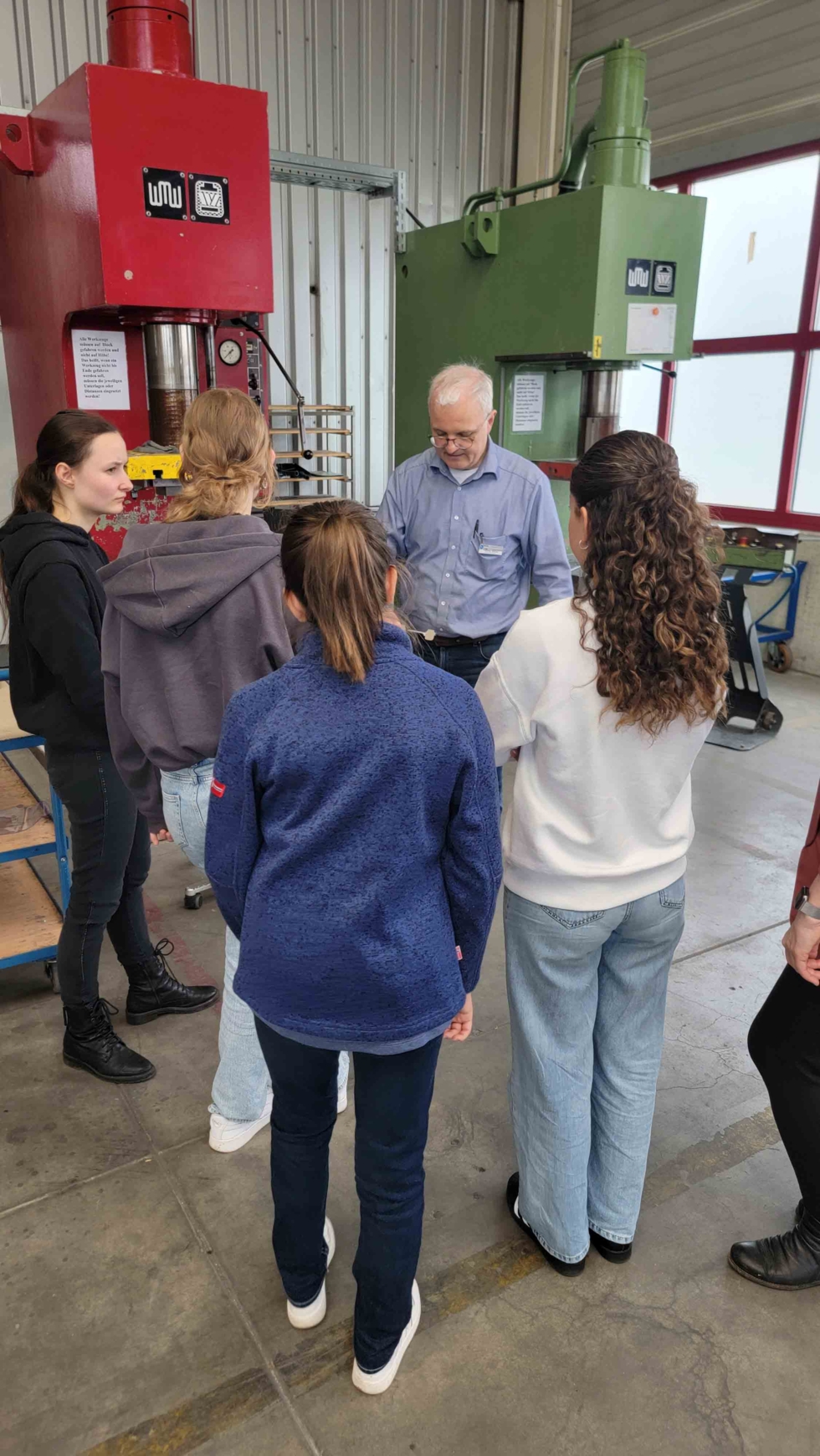 Mitarbeiter erklärt Girls'Day-Teilnehmerinnen einen Arbeitsprozess