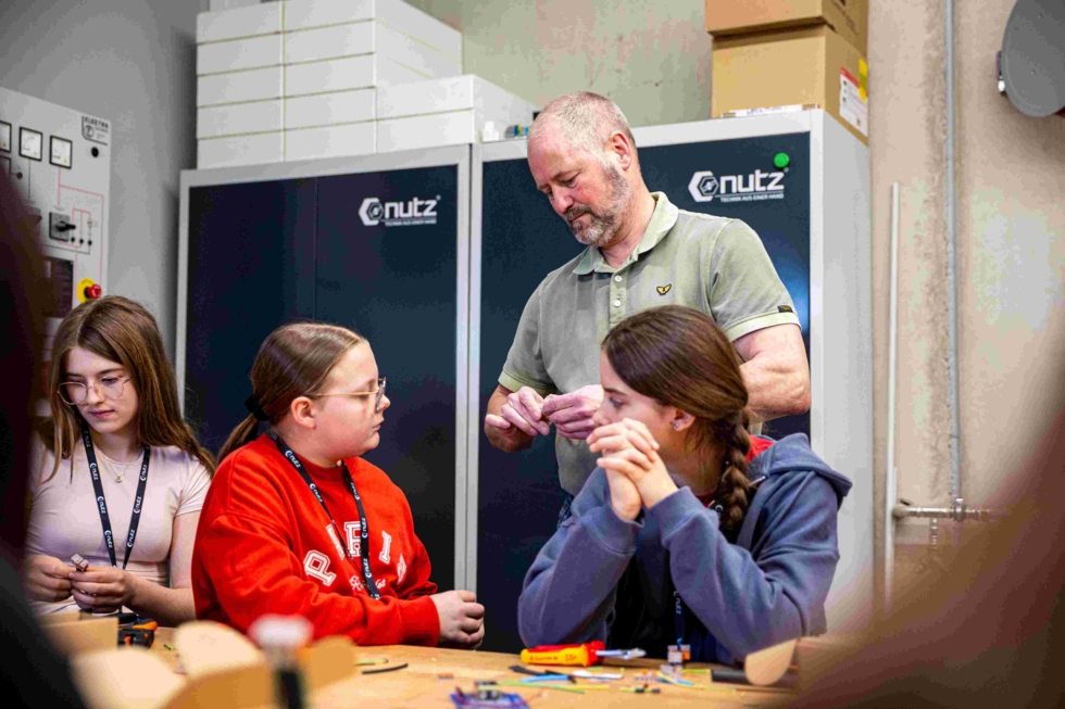 Ein Mitarbeiter erklärt den Girls' Day-Teilnehmerinnen den Umgang mit elektrischen Bauteilen