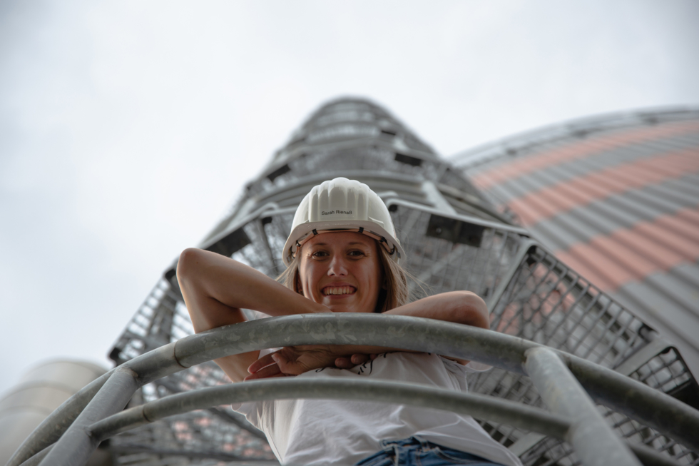 Junge Frau mit Helm lehnt an einer Brüstung