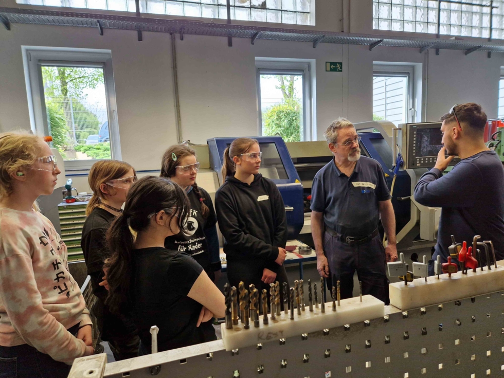 Girls'Day-Teilnehmerinnen mit Mitarbeitern in der Werkstatt