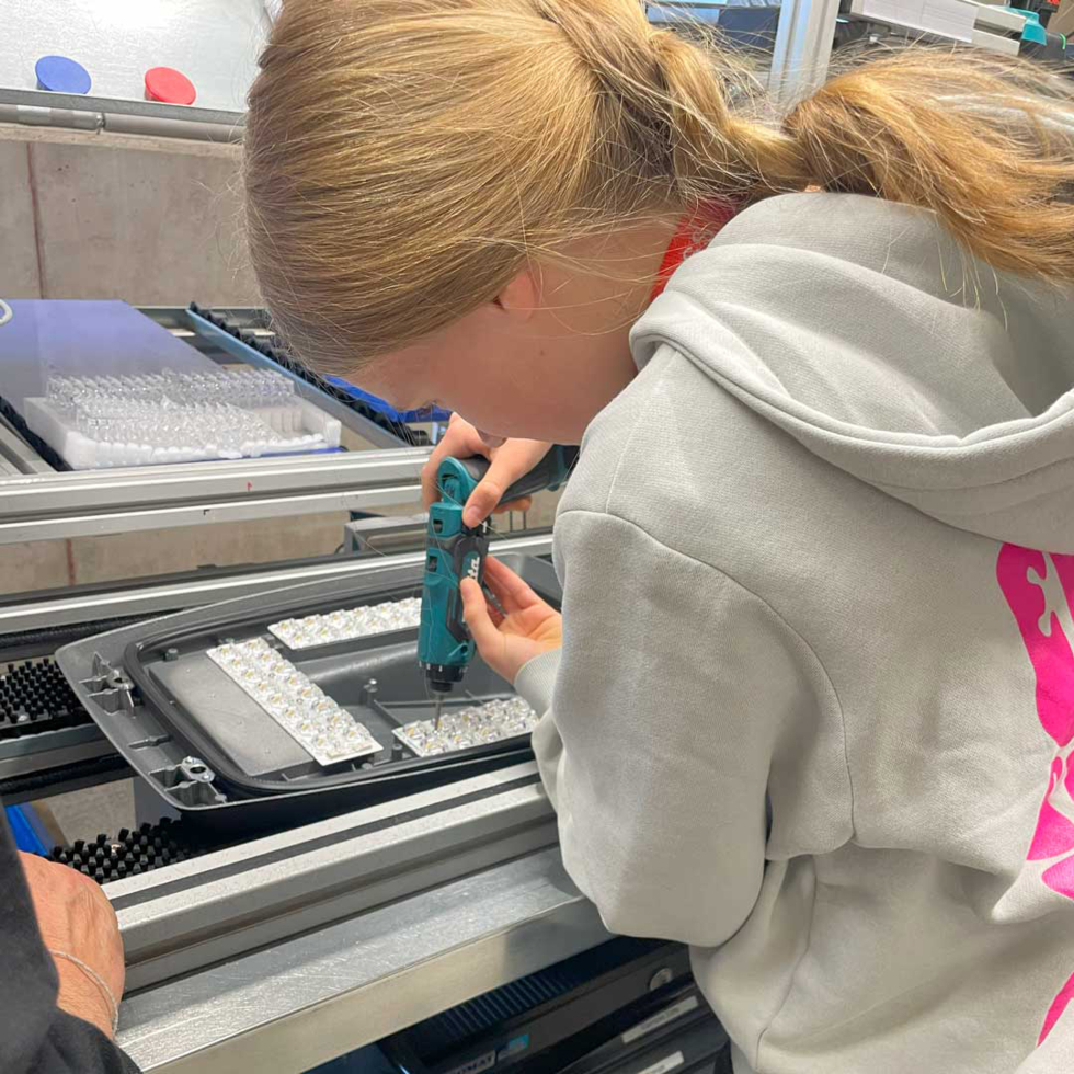 Girls' Day-Teilnehmerin arbeitet mit einem Akkuschrauber an einer Montagevorrichtung in einer Fabrik oder Werkstatt
