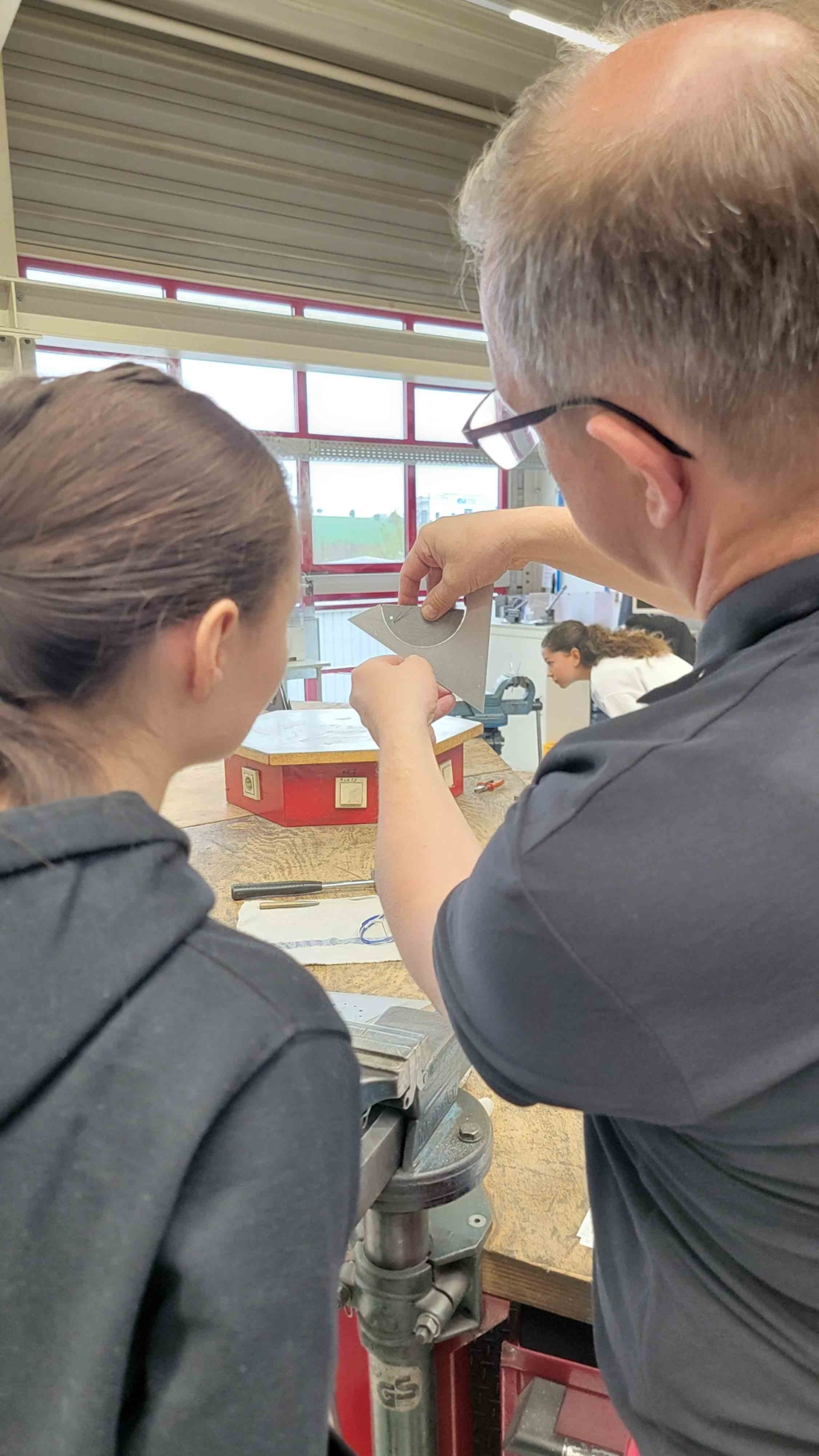 Mitarbeiter erklärt Girls'Day-Teilnehmerin einen Arbeitsprozess