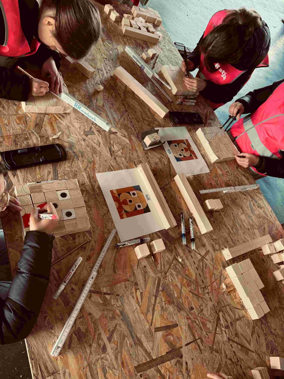 Girls'Day-Teilnehmerinnen mit Warnwesten bauen in Werkstatt mit Holz