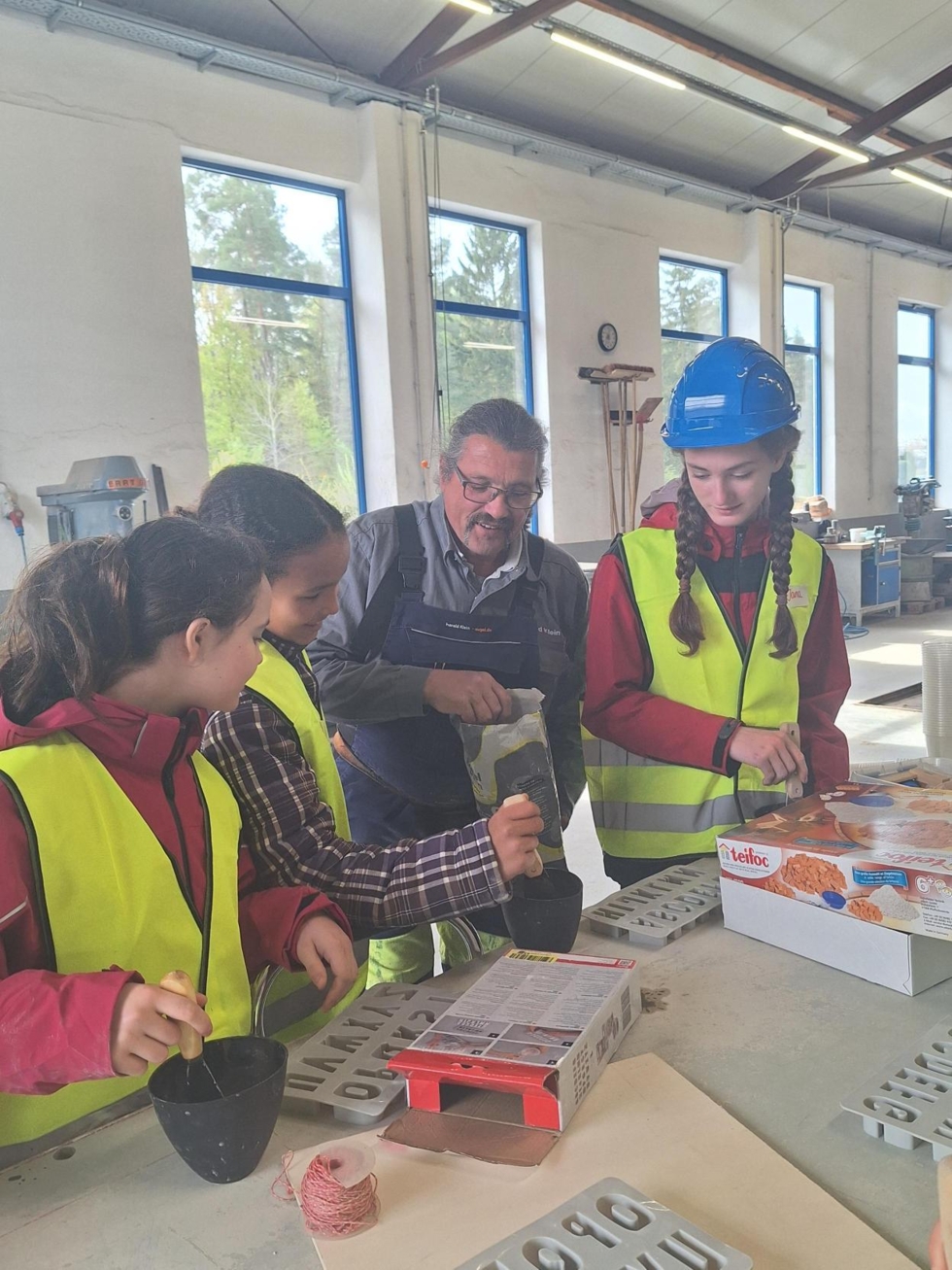 Girls'Day-Teilnehmerinnen arbeiten am Tisch mit Beton